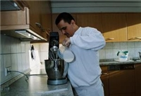 Mann stehend in der Küche, gießt Milch in eine Küchenmaschine