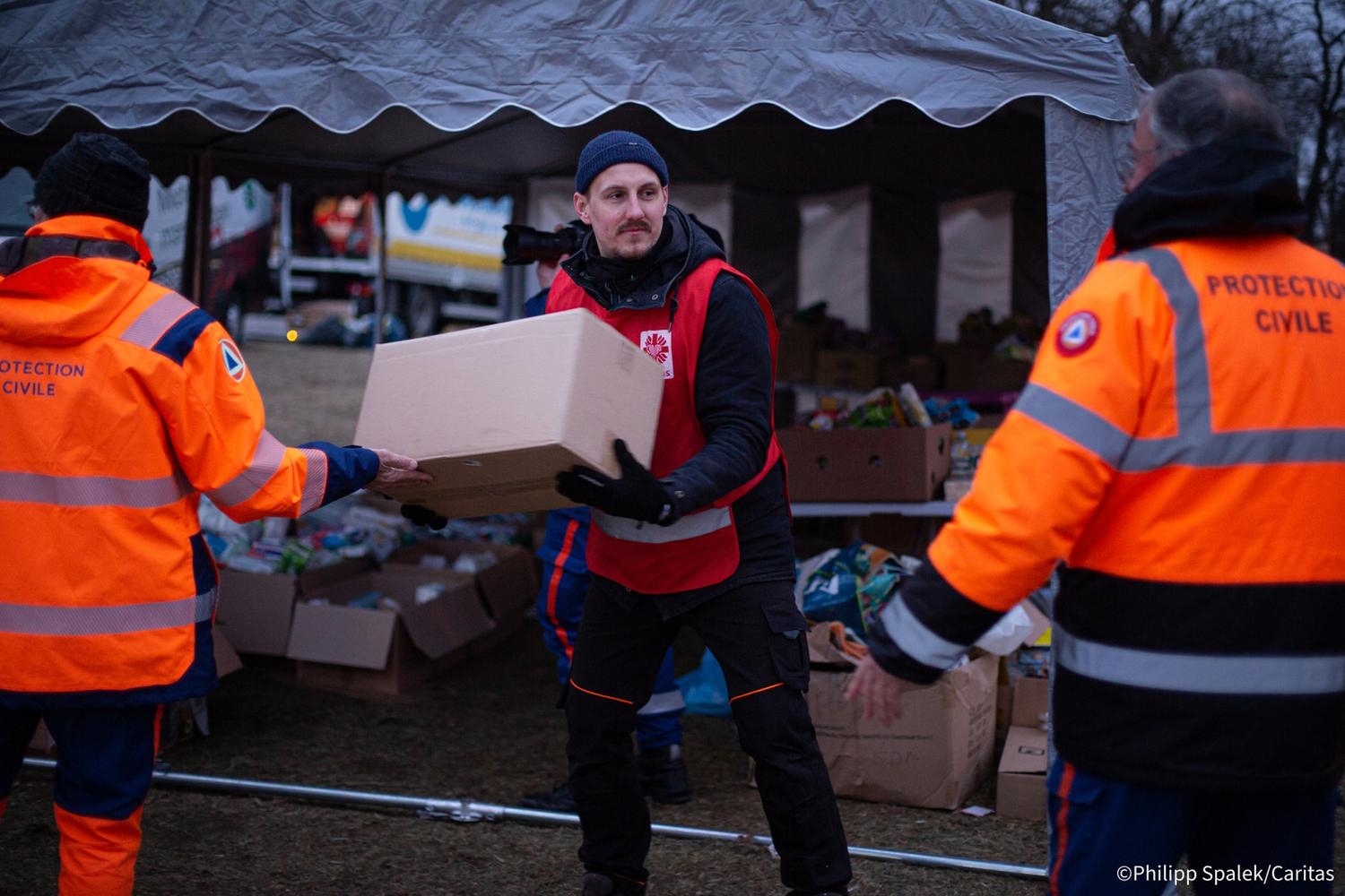 Caritas Mitarbeiter trägt Kiste mit Hilfsgütern